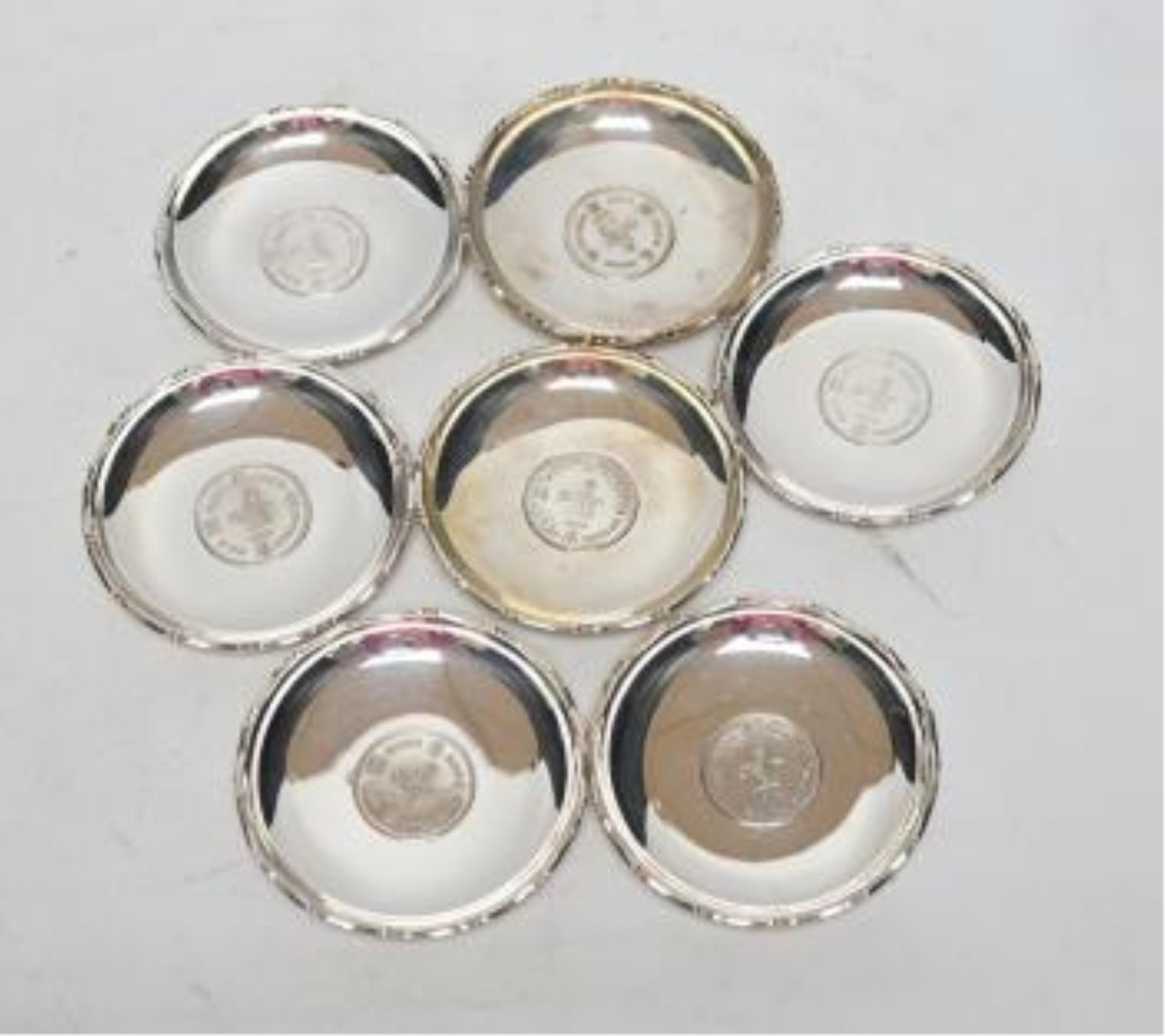 A set of seven Hong Kong sterling small dishes with inset coin, signed 'Sammy', diameter 86mm, gross weight 10.2oz. Good condition.